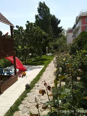a garden with a stone path with flowers and a bench at Акротирия Фешева in Nesebar
