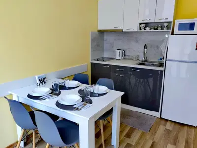 a kitchen with a white table with chairs and a white refrigerator at Pool Apartment Amadeus Lux in Sunny Beach