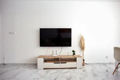 a living room with a tv on a white wall at Luxury First Line apartment with pool by the sea in Nesebar