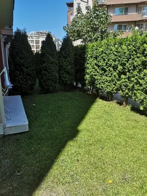 a yard with green grass and trees and a building at Studio VIP-ZONE in Sunny Beach