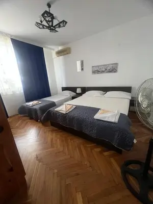 a hotel room with two beds and a fan at Апартамент Иванови in Pomorie