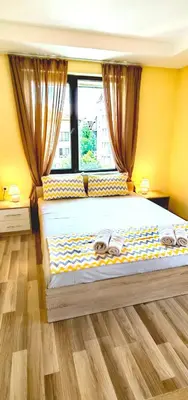a bedroom with a large bed with yellow walls and a window at Family Apartments Amadeus lux in Sunny Beach