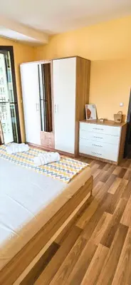 a bedroom with a large bed and a wooden floor at Family Apartments Amadeus lux in Sunny Beach