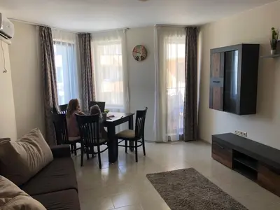 a woman sitting at a table in a living room at Rich-2 SP apartments in Ravda