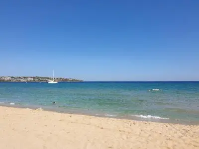 a sandy beach with a boat in the water at Studio Greenn Life Beach Resort in Sozopol