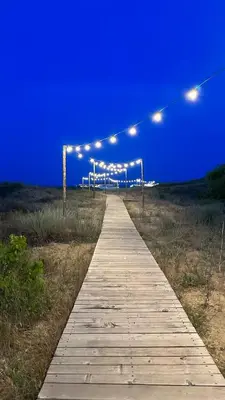 a wooden pathway with lights on the beach at night at Studio Greenn Life Beach Resort in Sozopol
