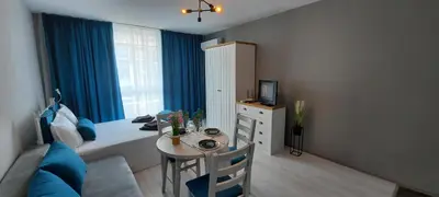 a living room with a table and blue curtains at A-19 Sea View Studio-Apartmen Sarafovo in Burgas City