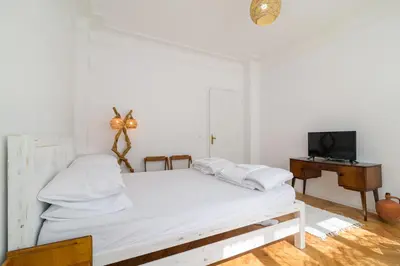 a white bedroom with a bed and a desk at Апартамент BOHO CHIC Free parking in Varna City