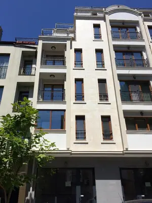 a tall white building with windows and a tree at Central Flat & Free Parking in Varna City