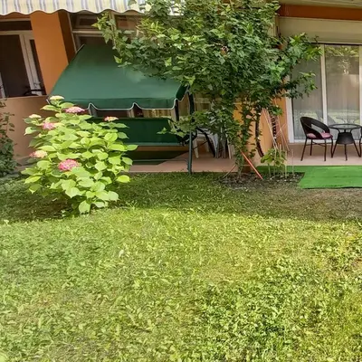 a garden with chairs and a table and a tree at Уютная квартира - студия в Старом Поморие, Болгария in Pomorie