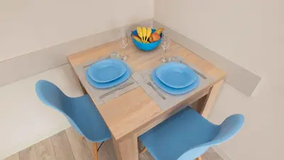 a wooden table with two blue chairs and a bowl of fruit at Студио Булаир 1 с безплатен паркинг in Burgas City