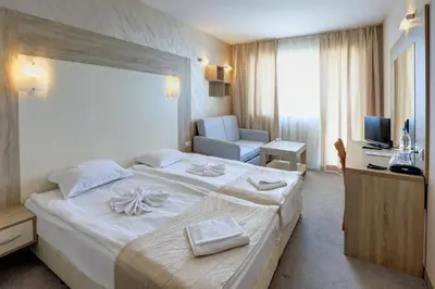 a hotel room with a large white bed and a desk at Paraiso Beach - All Inclusive in Obzor