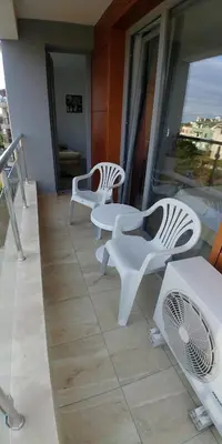 three white chairs and tables on a balcony at апартамент на брега на морето Бургас - Сарафово in Burgas City