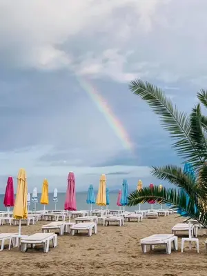 a rainbow over a beach with chairs and umbrellas at апартамент на брега на морето Бургас - Сарафово in Burgas City