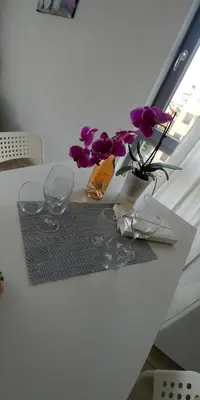 a table with two glasses and a vase with purple flowers at апартамент на брега на морето Бургас - Сарафово in Burgas City