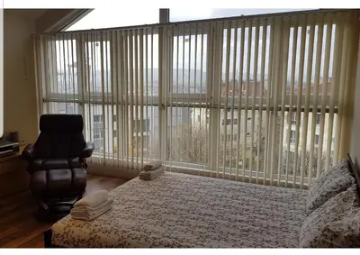 a bedroom with a bed and a chair and a large window at The Penthouse in Varna City