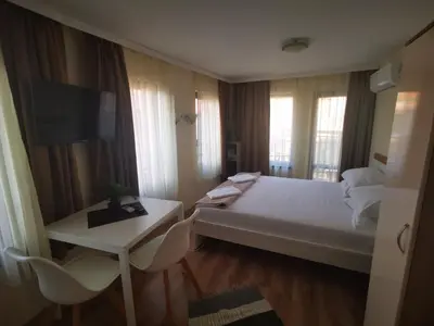 a hotel room with a large bed and a television at DAMARIS in Sozopol