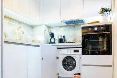 a washer and dryer in a kitchen with white cabinets at CASA ARTA in Burgas City