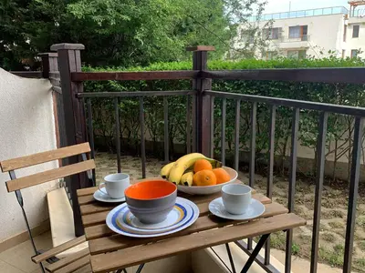 a wooden table with a bowl of fruit on a balcony at Бяла Виста Бийч Апартментс B - Byala Vista Beach Apartments B in Byala