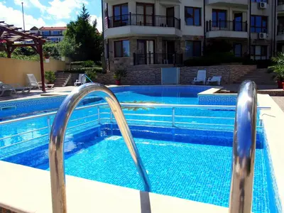 a swimming pool with two metal rails in front of a building at Бяла Виста Бийч Апартментс B - Byala Vista Beach Apartments B in Byala