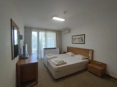 a hotel room with a bed and a television at СПА Апартаменти за ГОСТИ Затворен комплекс ЕМЕРАЛД in Ravda