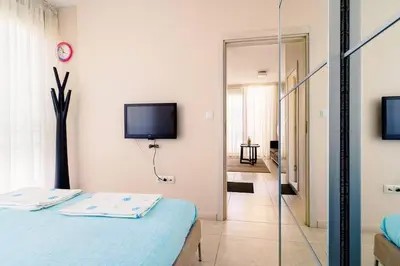 a bedroom with a bed and a tv on the wall at ЛУКСОЗНА ТРИЕТАЖНА КЪЩА в центъра на Приморско in Primorsko