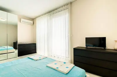 a bedroom with a bed and a tv on a dresser at ЛУКСОЗНА ТРИЕТАЖНА КЪЩА в центъра на Приморско in Primorsko