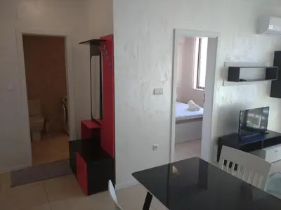 a living room with a table and a bedroom at Niya Apartments Kavaci Sozopol in Sozopol
