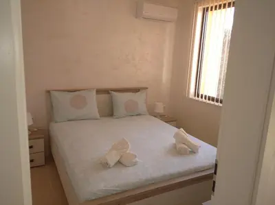 a white bed with two pairs of shoes on it at Niya Apartments Kavaci Sozopol in Sozopol