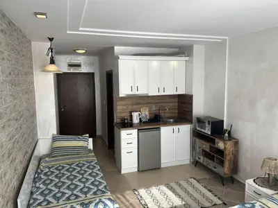 a kitchen with white cabinets and a bed in a room at Niya Apartments Kavaci Sozopol in Sozopol