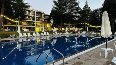 a pool with chairs and an umbrella next to a hotel at Queen Nelly Park in Kiten