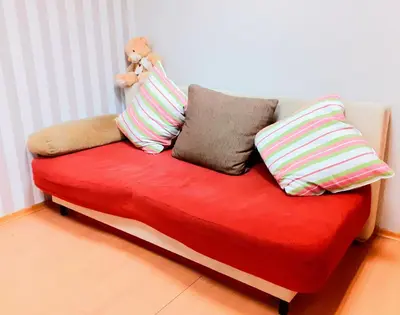 a red couch with pillows and a teddy bear on it at DOWNTOWN - BEST Price Small Apartment in Burgas City