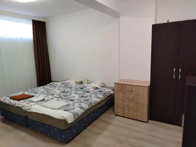 a bedroom with a bed and a wooden cabinet at Apartments Sarafovo in Burgas City