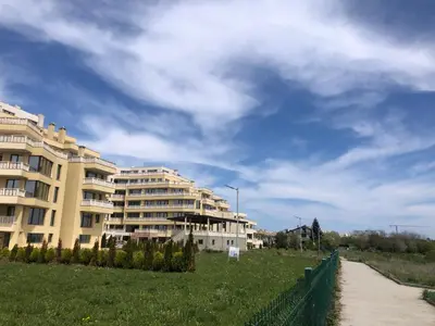 a building with a fence next to a grass field at Apartments Sarafovo in Burgas City