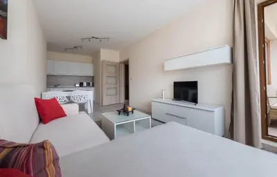 a living room with a white couch and a kitchen at Stoyanov South Bay - Varna in Varna City