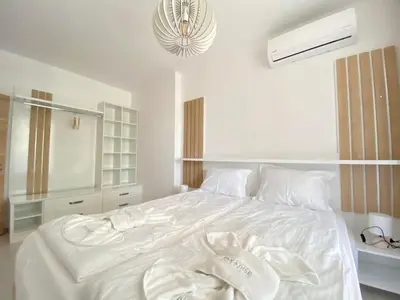 a white bed in a bedroom with a chandelier at The Green Paradise Apartments in Primorsko