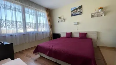 a bedroom with a purple bed and a large window at SUMMER BREEZE 406 Studio Sunny Beach in Sunny Beach