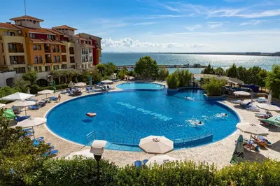 a large swimming pool with chairs and umbrellas at Аpartments Comfort -Marina Cape in Aheloy