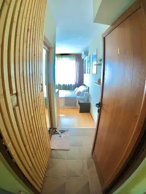 a hallway with a wooden door and a living room at Sunset Yavorov Pomorie in Pomorie