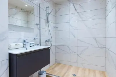 a white bathroom with a sink and a shower at Green Luxury Apartments in Burgas City