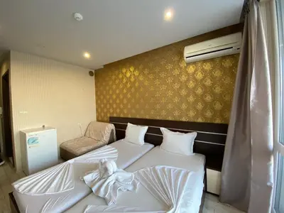 a room with two beds and a chair in it at PARADISO B 210 Private Sea View Studio NESSEBAR in Nesebar