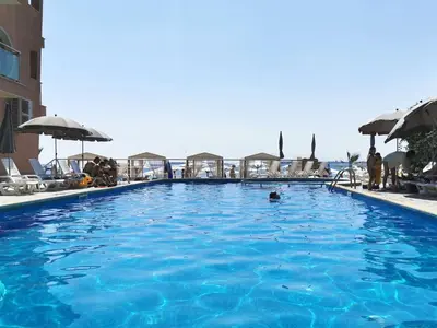 a large swimming pool with blue water and umbrellas at Beachfront Apartments by Marty's in Sunny Beach