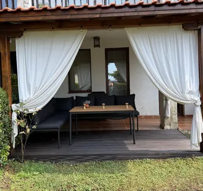 a wooden patio with a table and curtains at Manastira-2 (A-3) in Sveti Vlas