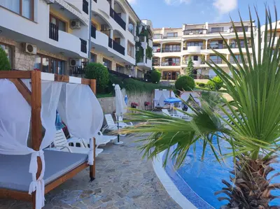 a resort with a pool and chairs and a building at Sun Coast Apartment in Sveti Vlas