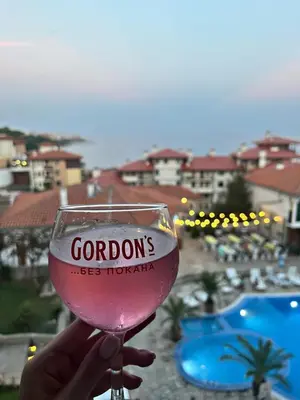 a person holding a glass of wine in front of a resort at Sun Coast Apartment in Sveti Vlas