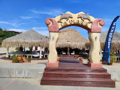 an entrance to a resort with an arch and straw umbrellas at Sun Coast Apartment in Sveti Vlas