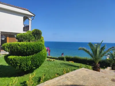 a hedge letter e in front of a house with the ocean at Sun Coast Apartment in Sveti Vlas