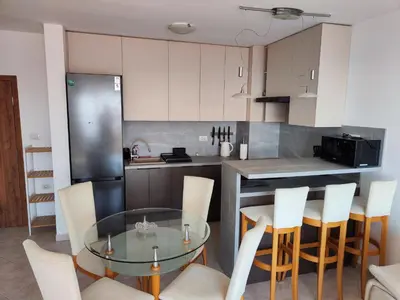 a kitchen with a glass table and white chairs at Sun Coast Apartment in Sveti Vlas