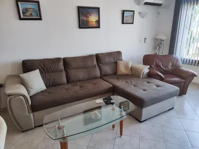 a living room with a brown couch and a glass table at Sun Coast Apartment in Sveti Vlas