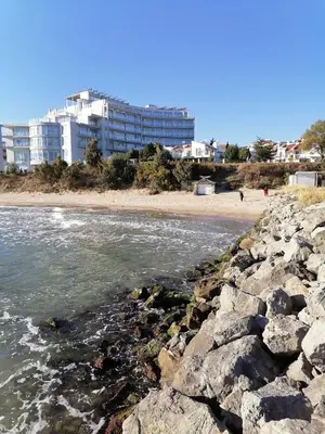 a view of a beach with buildings in the background at Helios 350m from the beach in Sveti Vlas